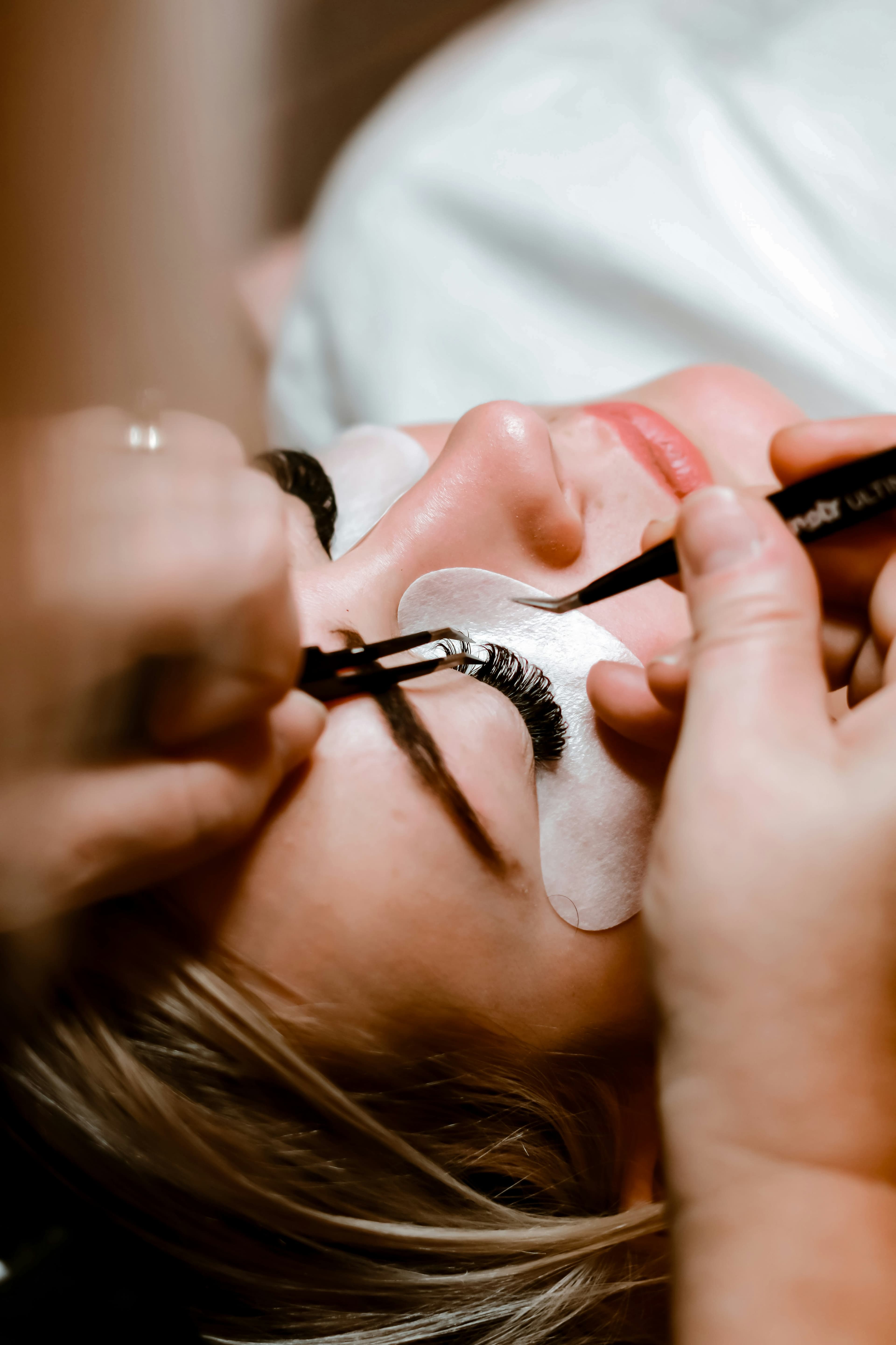 Lash artist applying eyelash extensions to a client